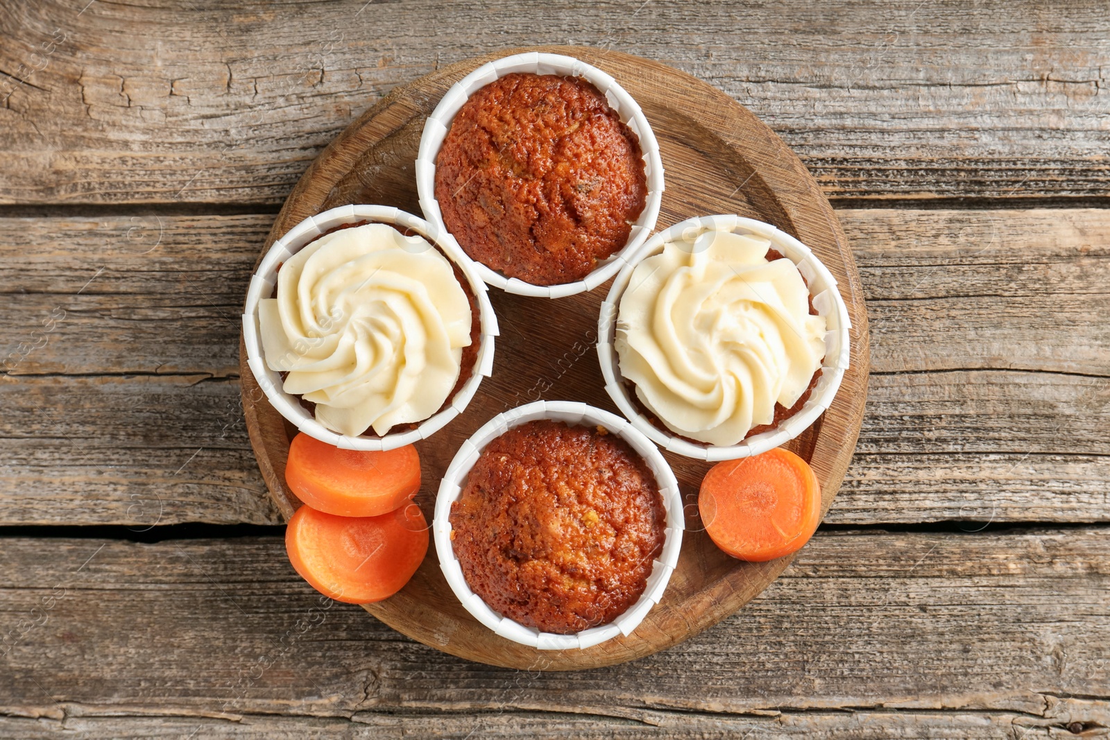 Photo of Tasty carrot muffins and fresh vegetable on wooden table, top view