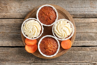 Photo of Tasty carrot muffins and fresh vegetable on wooden table, top view