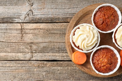 Photo of Tasty carrot muffins and fresh vegetable on wooden table, top view. Space for text