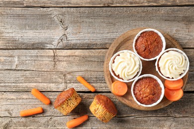 Photo of Delicious carrot muffins and fresh vegetables on wooden table, flat lay. Space for text