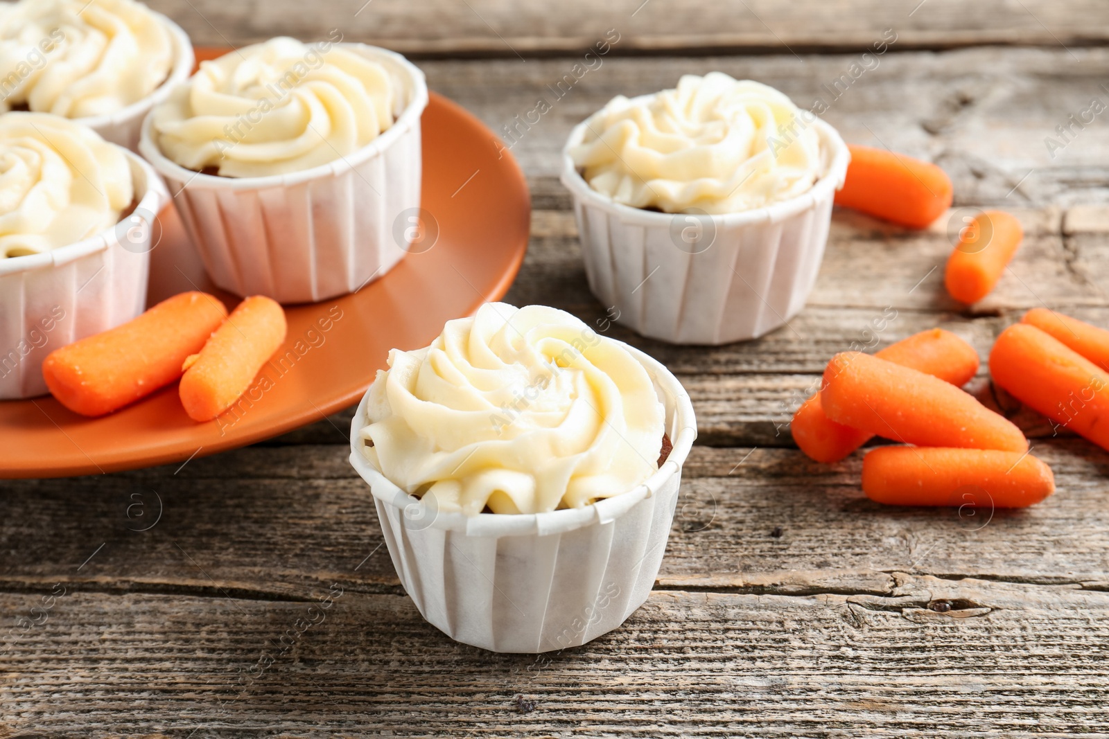 Photo of Delicious carrot muffins and fresh vegetables on wooden table, closeup