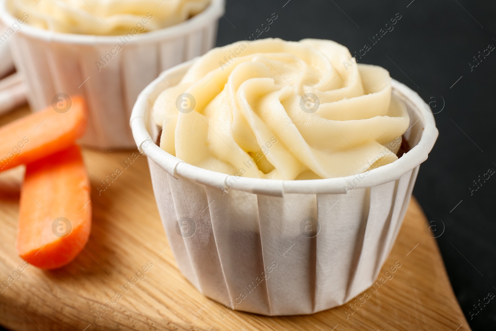 Photo of Tasty carrot muffins with fresh vegetable on black table, closeup