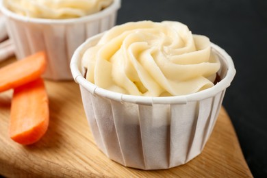 Photo of Tasty carrot muffins with fresh vegetable on black table, closeup