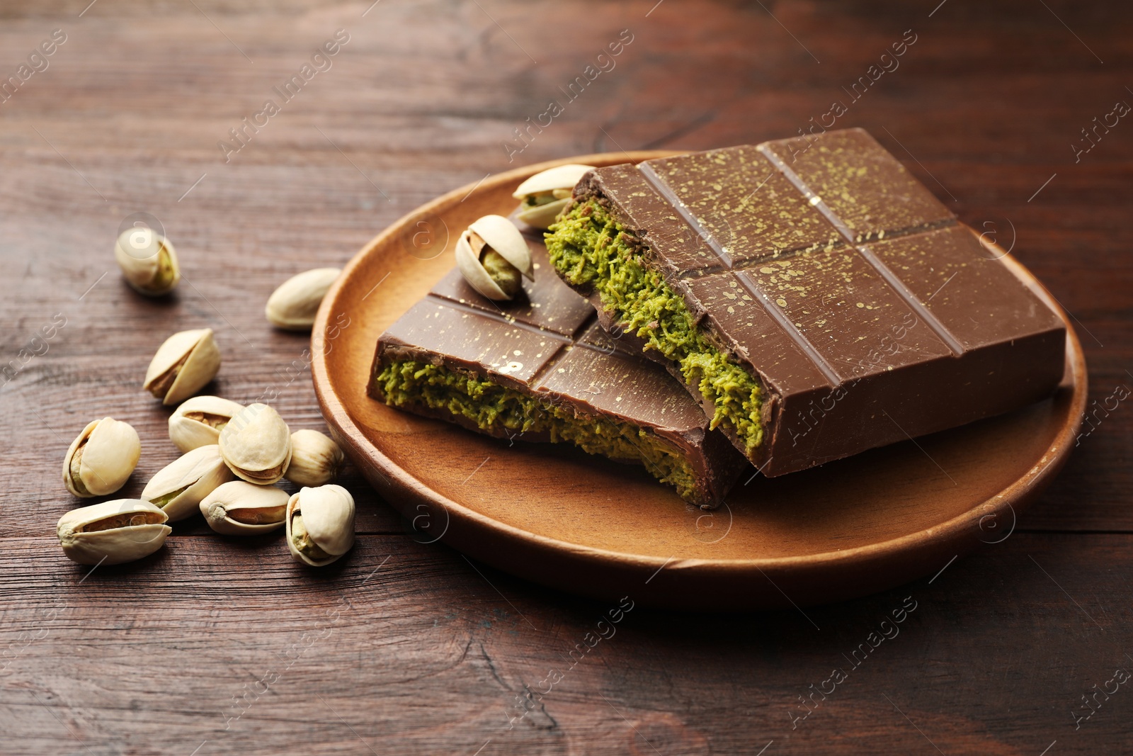 Photo of Pieces of tasty Dubai chocolate with pistachios and knafeh on wooden table, closeup