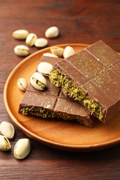 Photo of Pieces of tasty Dubai chocolate with pistachios and knafeh on wooden table, closeup