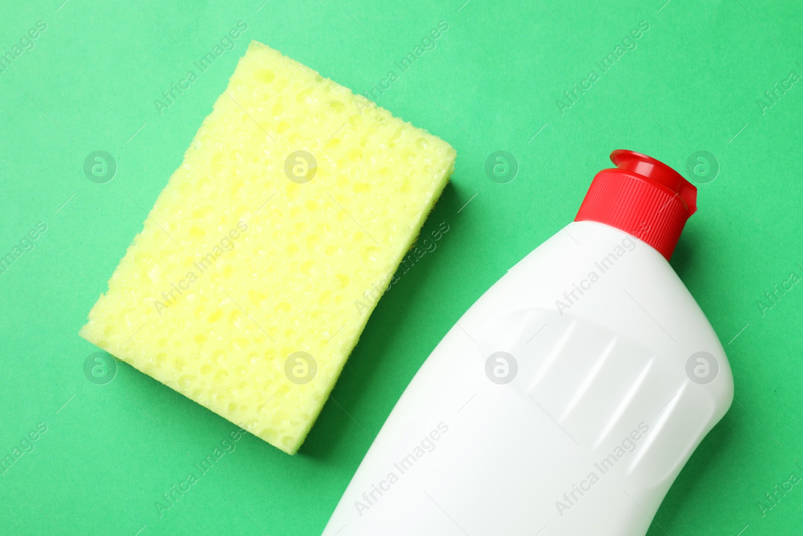 Photo of Sponge and dish soap on green background, top view