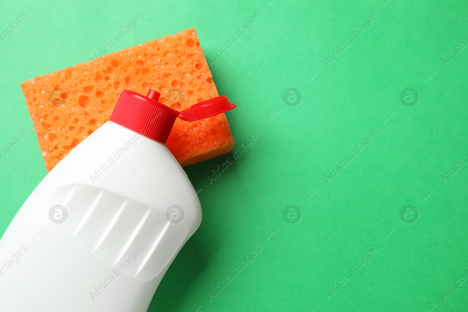 Photo of Sponge and dish soap on green background, top view. Space for text