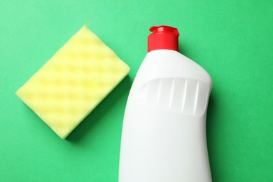 Photo of Sponge and dish soap on green background, top view