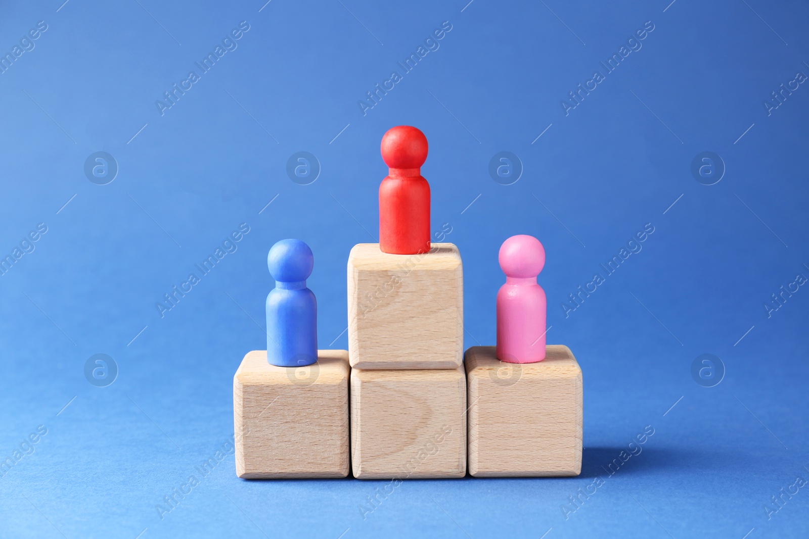 Photo of Competition concept. Human figures on wooden cubes against blue background