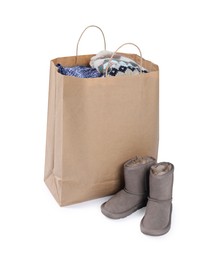 Photo of Used clothes in paper bag and boots isolated on white