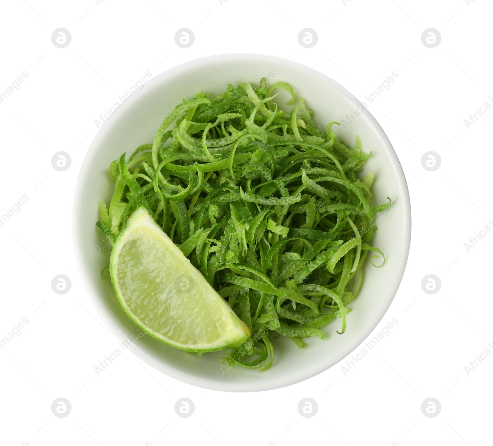 Photo of Lime zest and piece of fruit in bowl isolated on white, top view