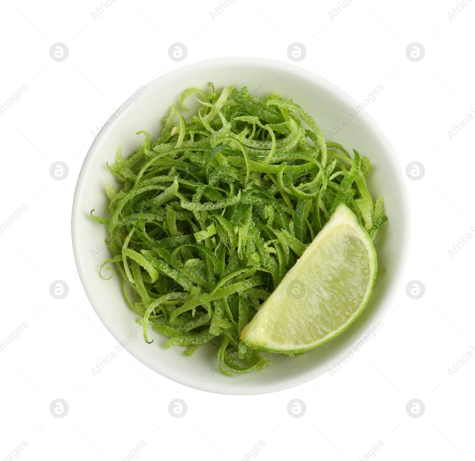 Photo of Lime zest and piece of fruit in bowl isolated on white, top view