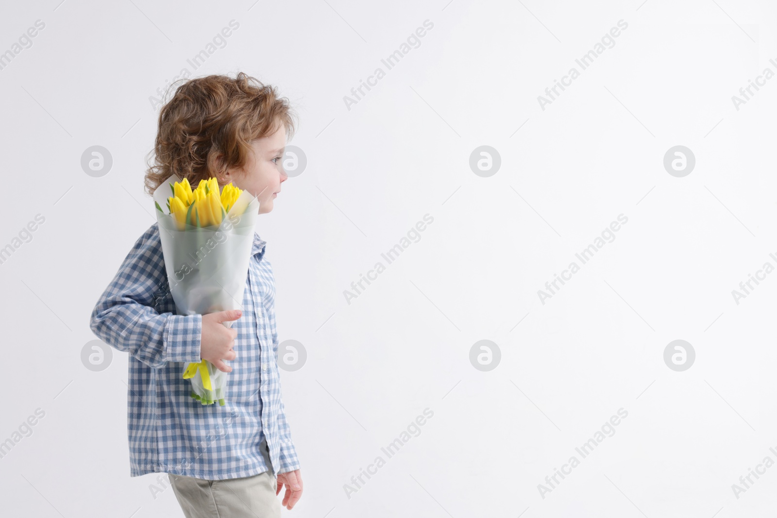 Photo of Cute little boy with bouquet of tulips on white background. Space for text