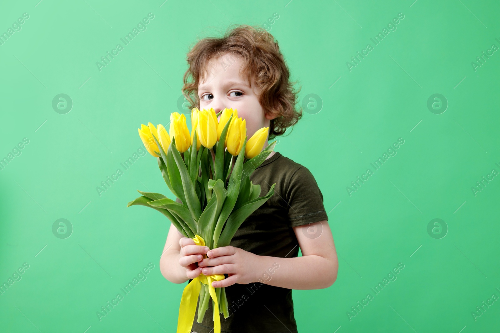 Photo of Cute little boy with bouquet of tulips on green background