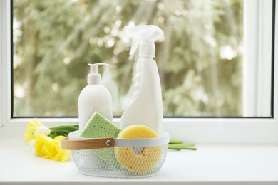 Photo of Spring cleaning. Detergents, supplies and flowers on windowsill indoors, space for text