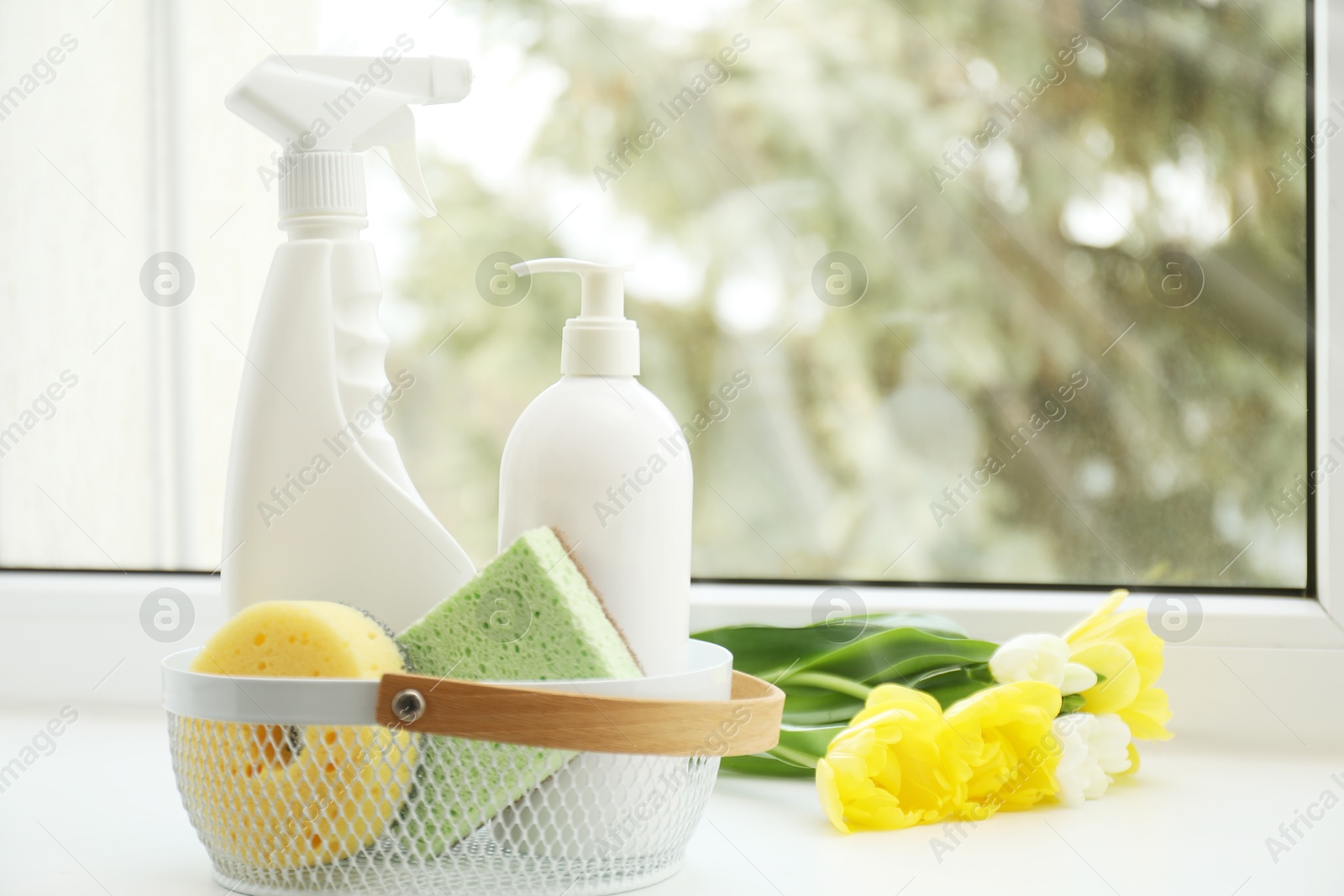 Photo of Spring cleaning. Detergents, supplies and flowers on windowsill indoors