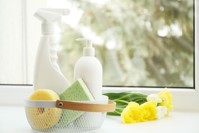 Photo of Spring cleaning. Detergents, supplies and flowers on windowsill indoors