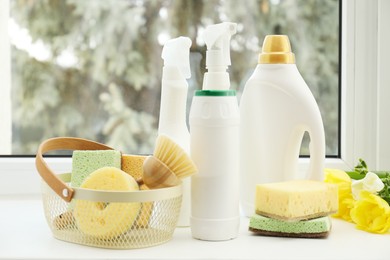 Photo of Spring cleaning. Detergents, supplies and flowers on windowsill indoors