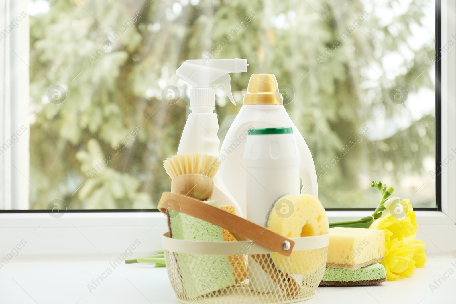 Photo of Spring cleaning. Detergents, supplies and flowers on windowsill indoors