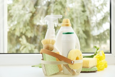 Photo of Spring cleaning. Detergents, supplies and flowers on windowsill indoors