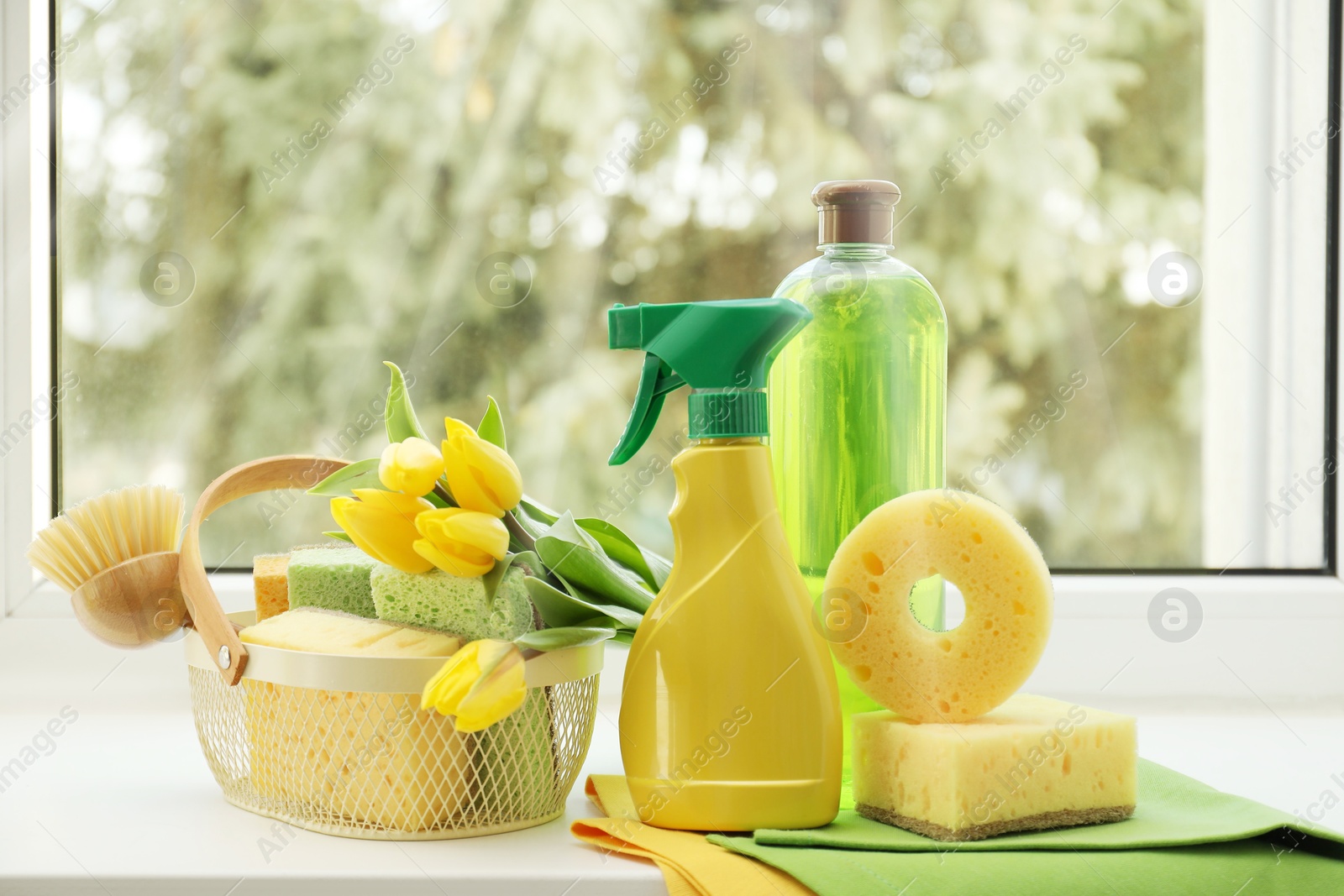 Photo of Spring cleaning. Detergents, supplies and tulips on windowsill indoors