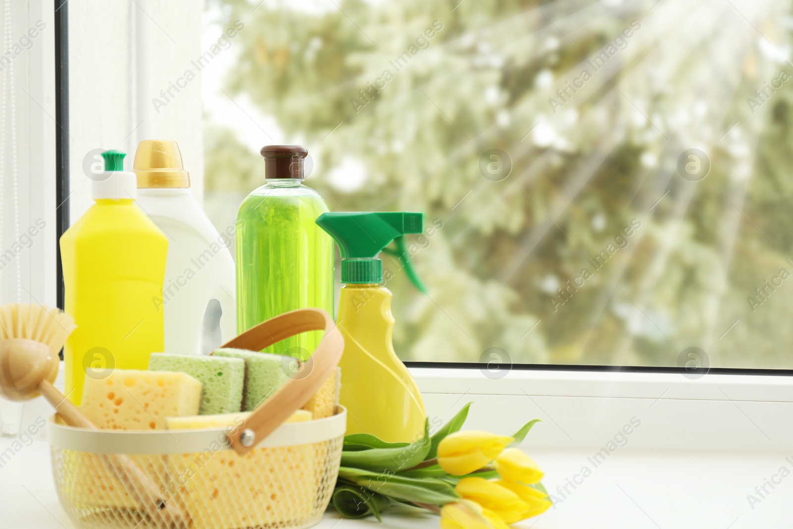 Photo of Spring cleaning. Detergents, supplies and tulips on windowsill indoors, space for text