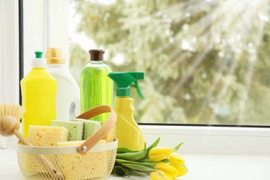 Photo of Spring cleaning. Detergents, supplies and tulips on windowsill indoors, space for text