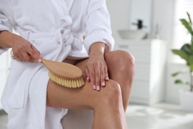 Photo of Woman doing anti cellulite massage with brush indoors, closeup