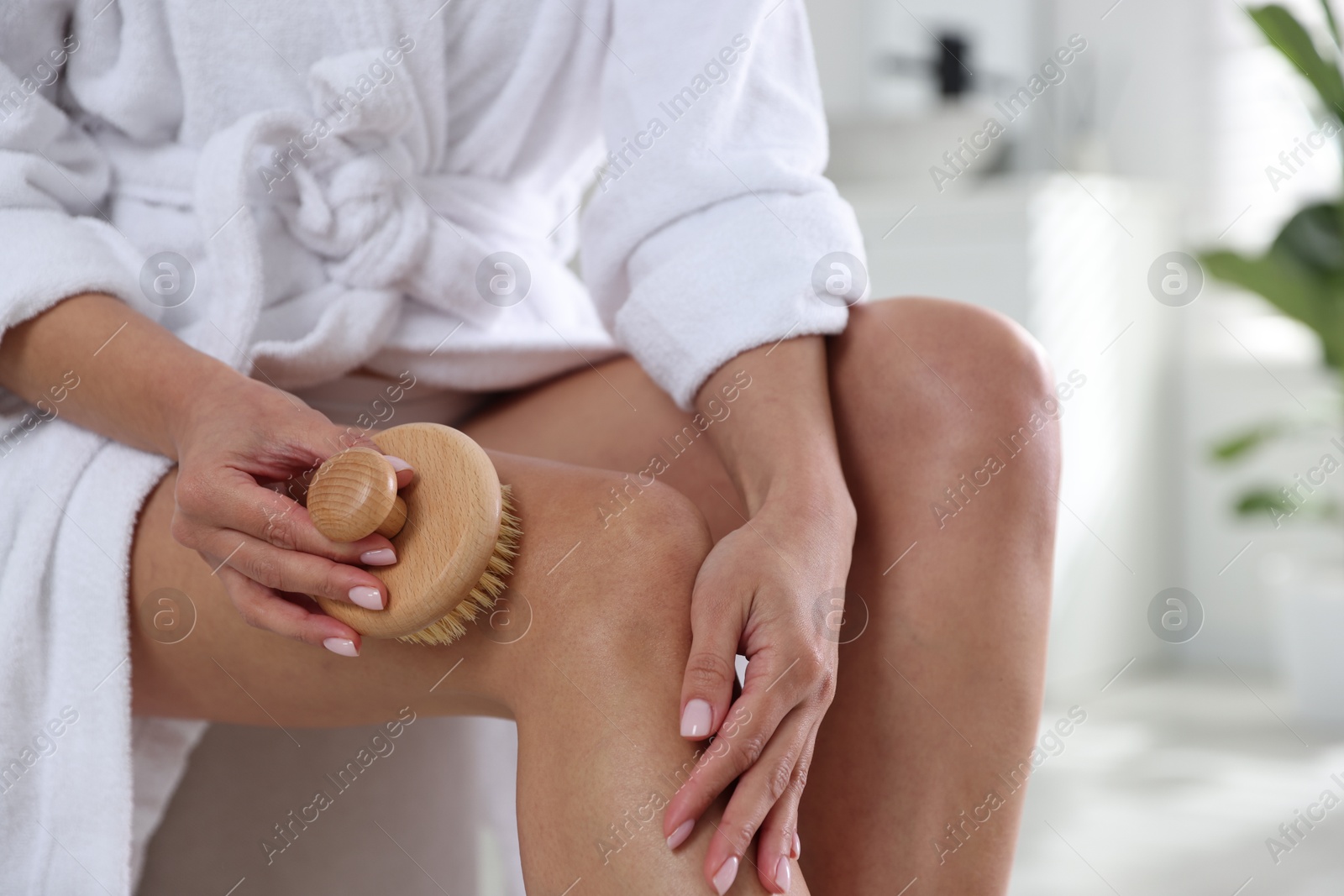 Photo of Woman doing anti cellulite massage with brush indoors, closeup