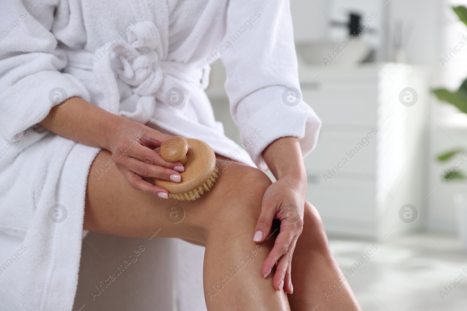 Photo of Woman doing anti cellulite massage with brush indoors, closeup