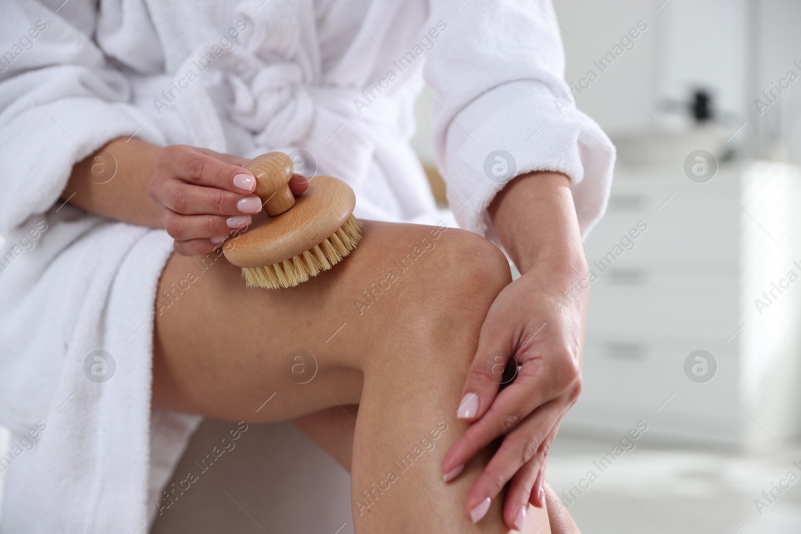 Photo of Woman doing anti cellulite massage with brush indoors, closeup