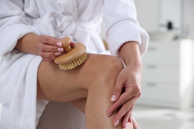 Photo of Woman doing anti cellulite massage with brush indoors, closeup