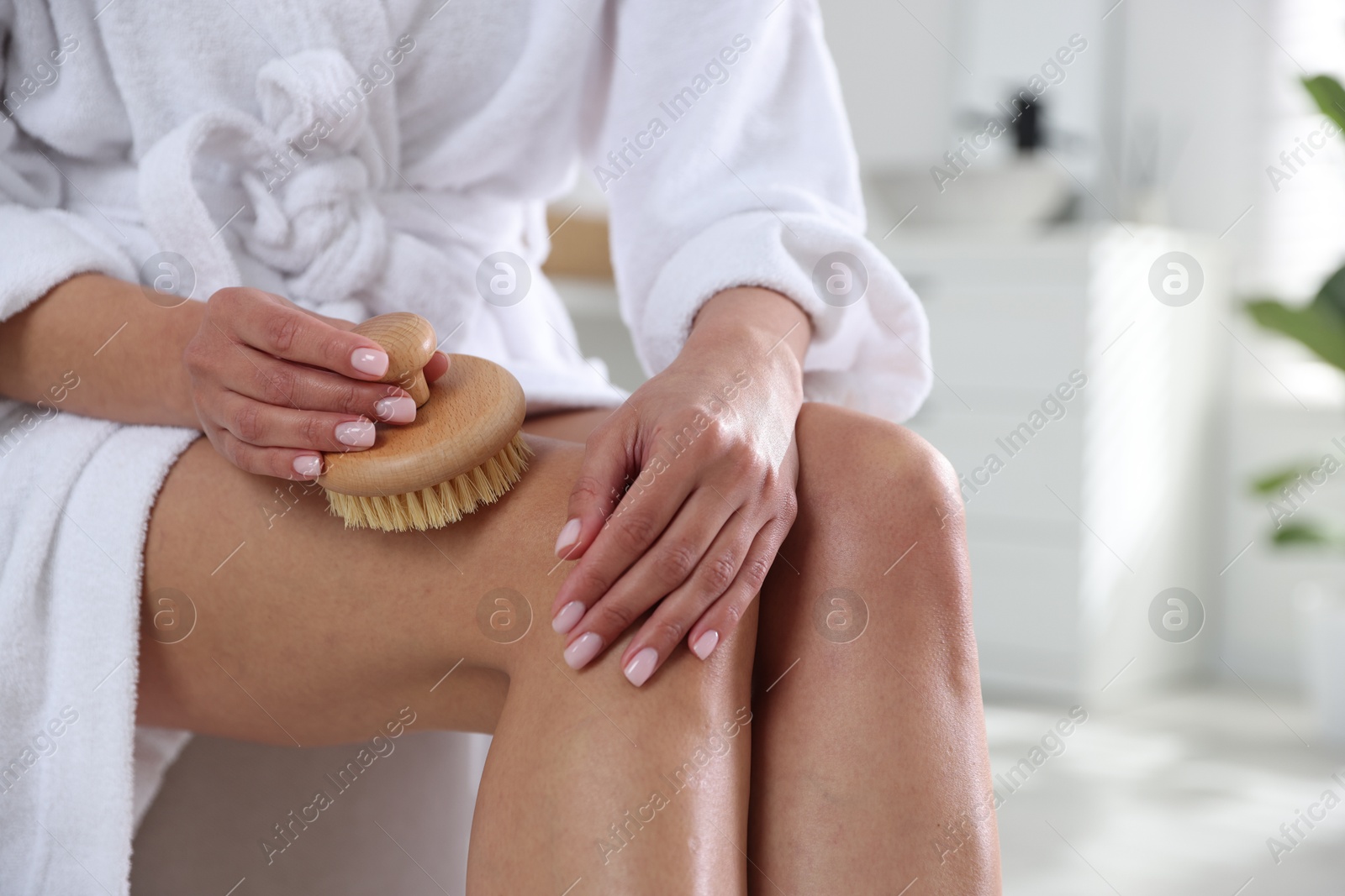 Photo of Woman doing anti cellulite massage with brush indoors, closeup