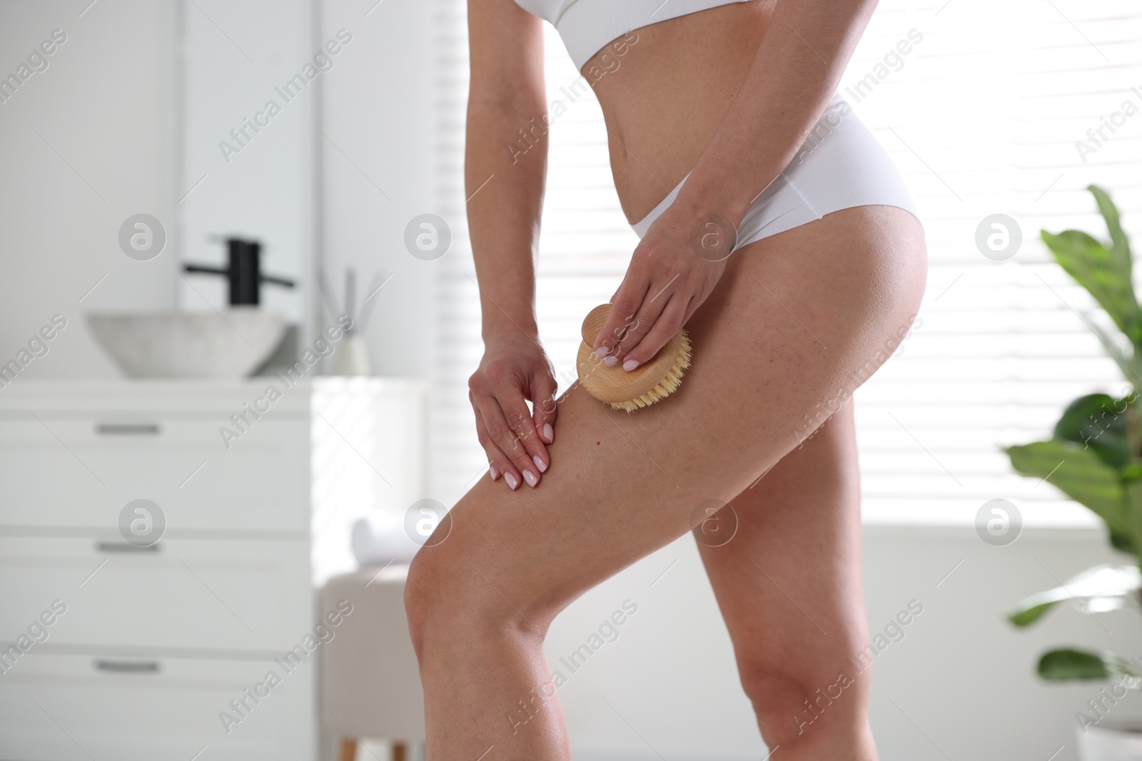 Photo of Woman doing anti cellulite massage with brush indoors, closeup. Space for text