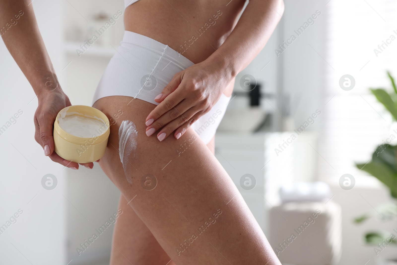 Photo of Woman applying anti cellulite cream indoors, closeup