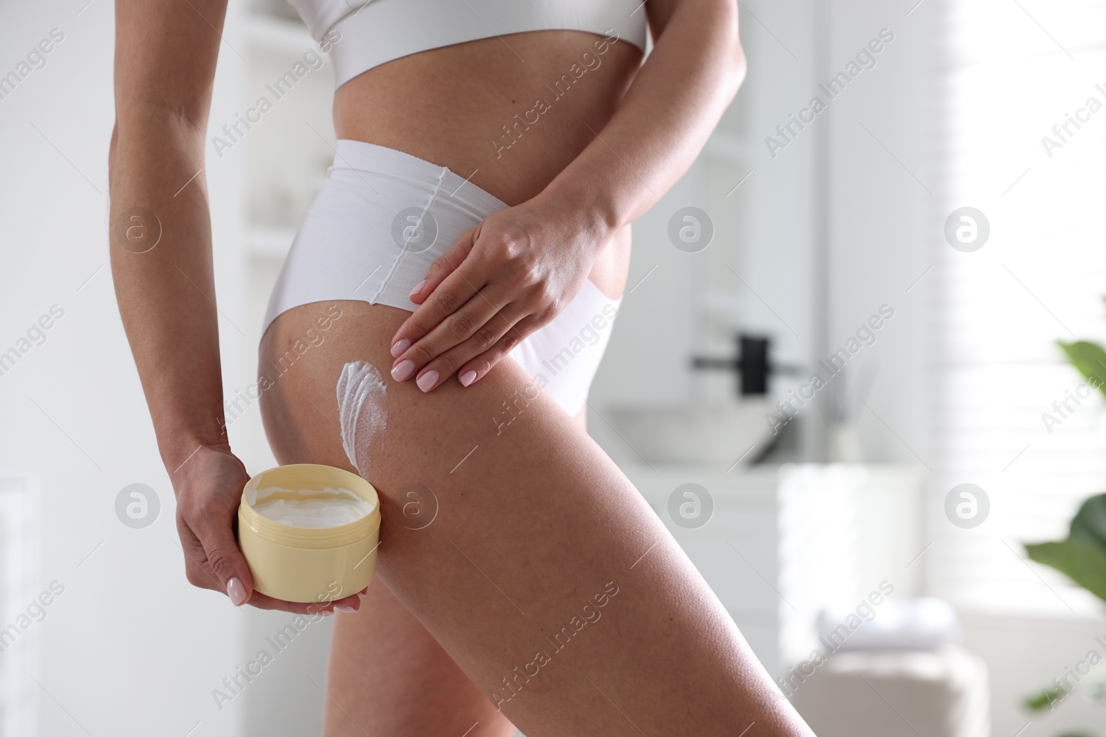 Photo of Woman applying anti cellulite cream indoors, closeup. Space for text