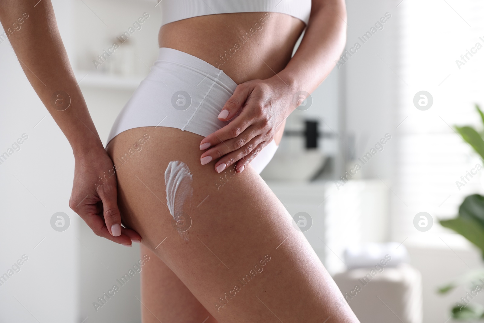 Photo of Woman applying anti cellulite cream indoors, closeup