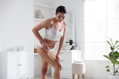 Woman doing anti cellulite massage with brush indoors. Space for text