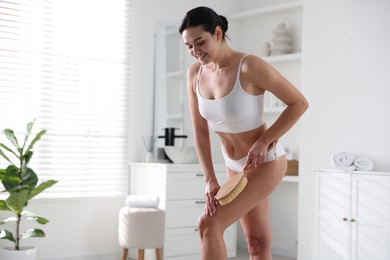 Photo of Woman doing anti cellulite massage with brush indoors. Space for text