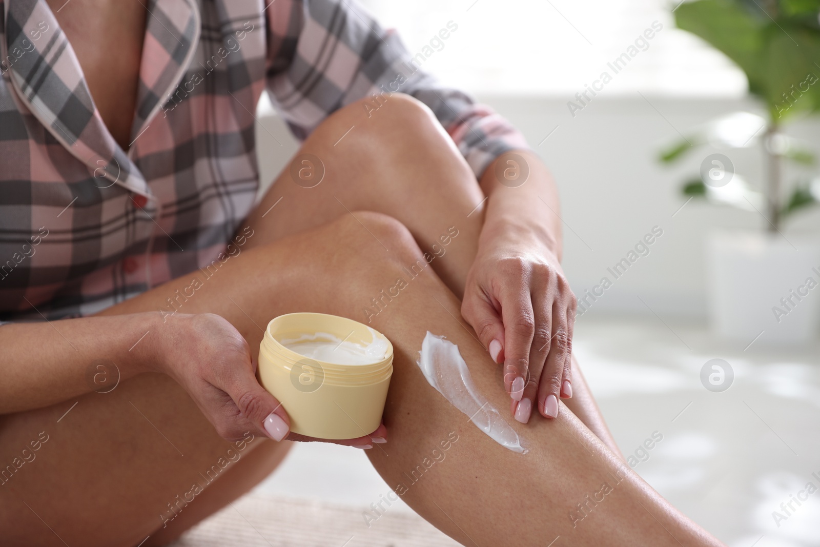 Photo of Woman applying anti cellulite cream indoors, closeup