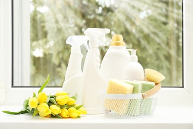 Photo of Spring cleaning. Detergents, supplies and tulips on windowsill indoors