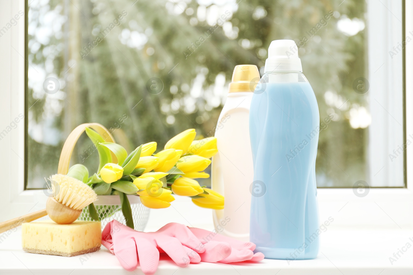 Photo of Spring cleaning. Detergents, supplies and tulips on windowsill indoors