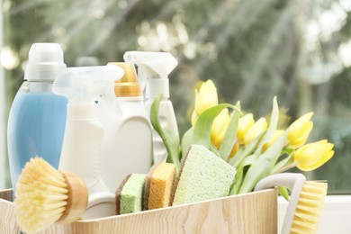 Photo of Spring cleaning. Detergents, supplies and tulips on windowsill indoors, closeup