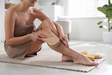 Woman doing anti cellulite massage with brush indoors, closeup. Space for text