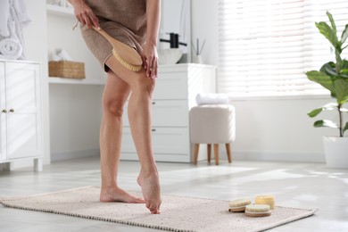 Woman doing anti cellulite massage with brush indoors, closeup. Space for text