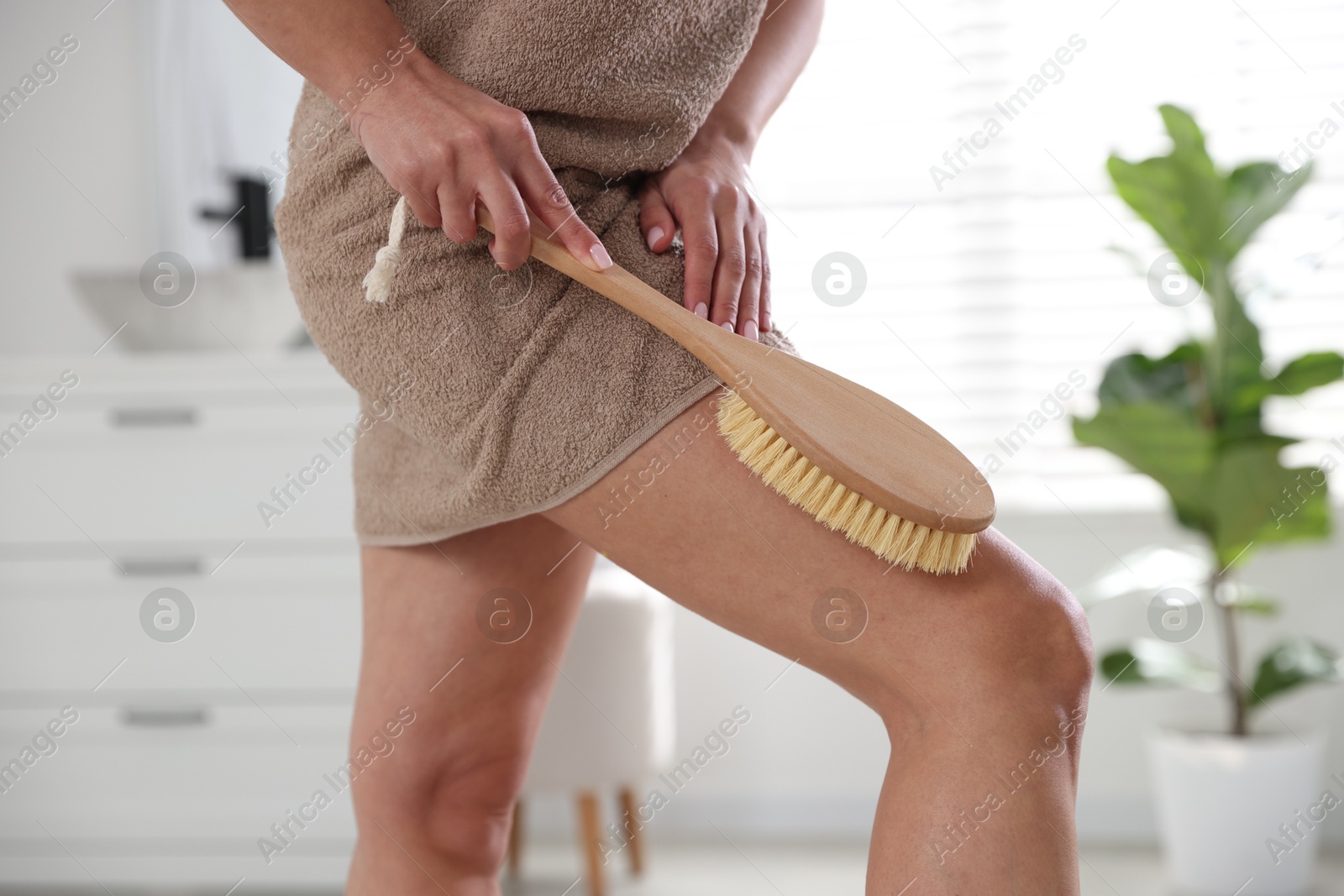 Photo of Woman doing anti cellulite massage with brush indoors, closeup