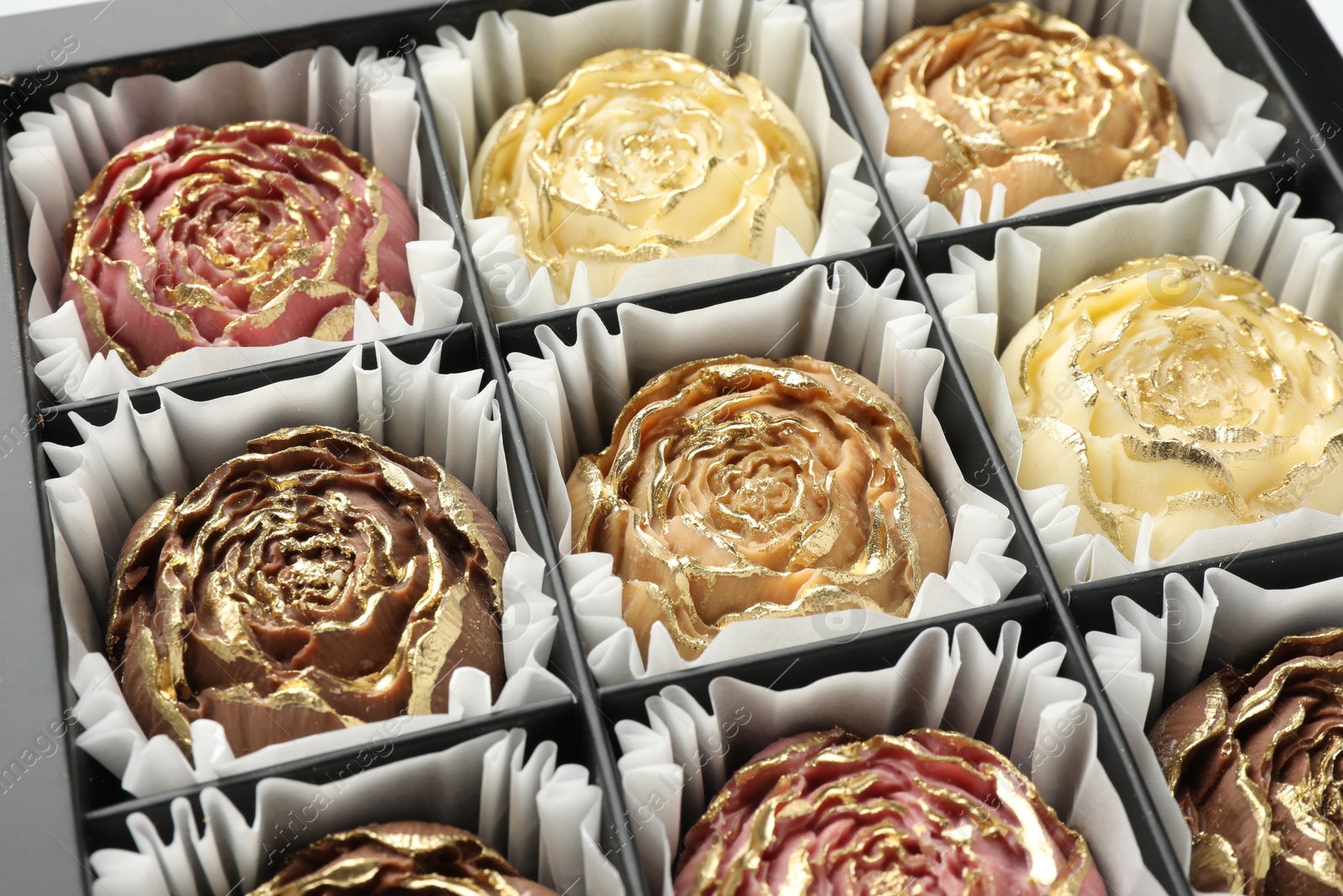 Photo of Flower shaped chocolate bonbons in box, closeup