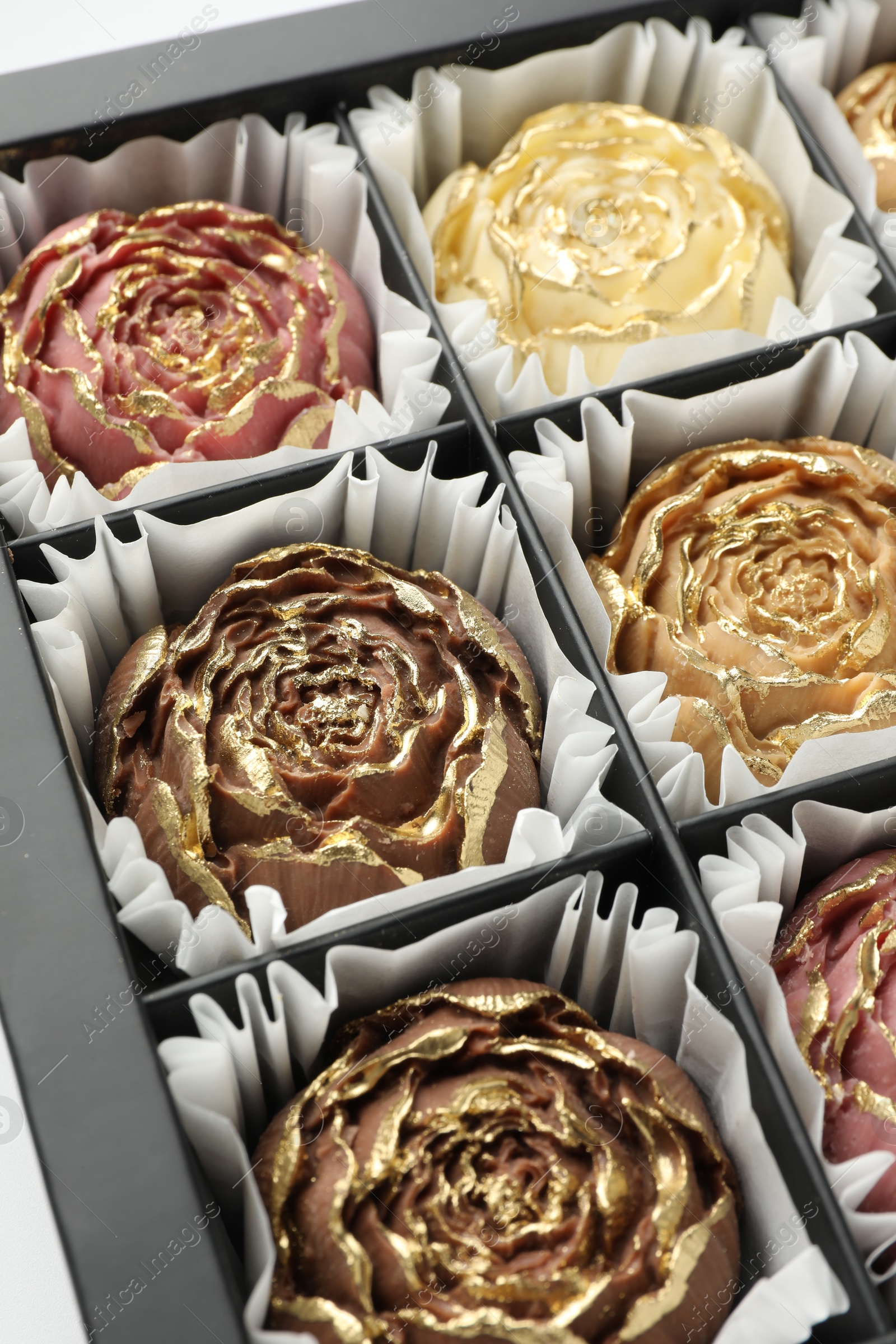 Photo of Flower shaped chocolate bonbons in box, closeup