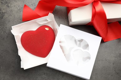 Photo of Heart shaped chocolate and gift box on grey table, flat lay