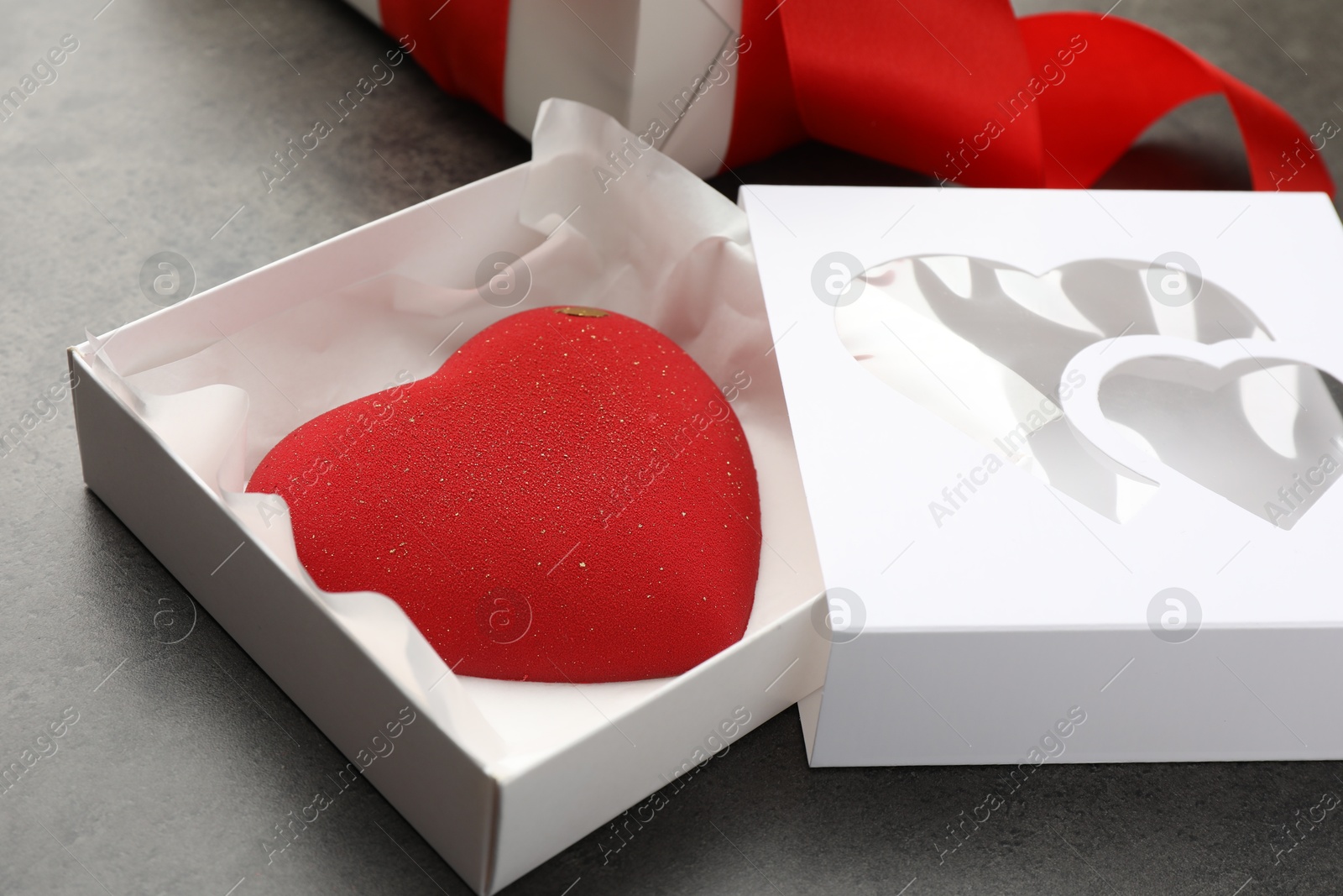 Photo of Heart shaped chocolate in box on grey table, closeup